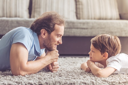 Father & son laying on floor looking at each other