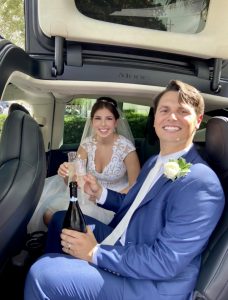 Bride and groom in car with prosecco